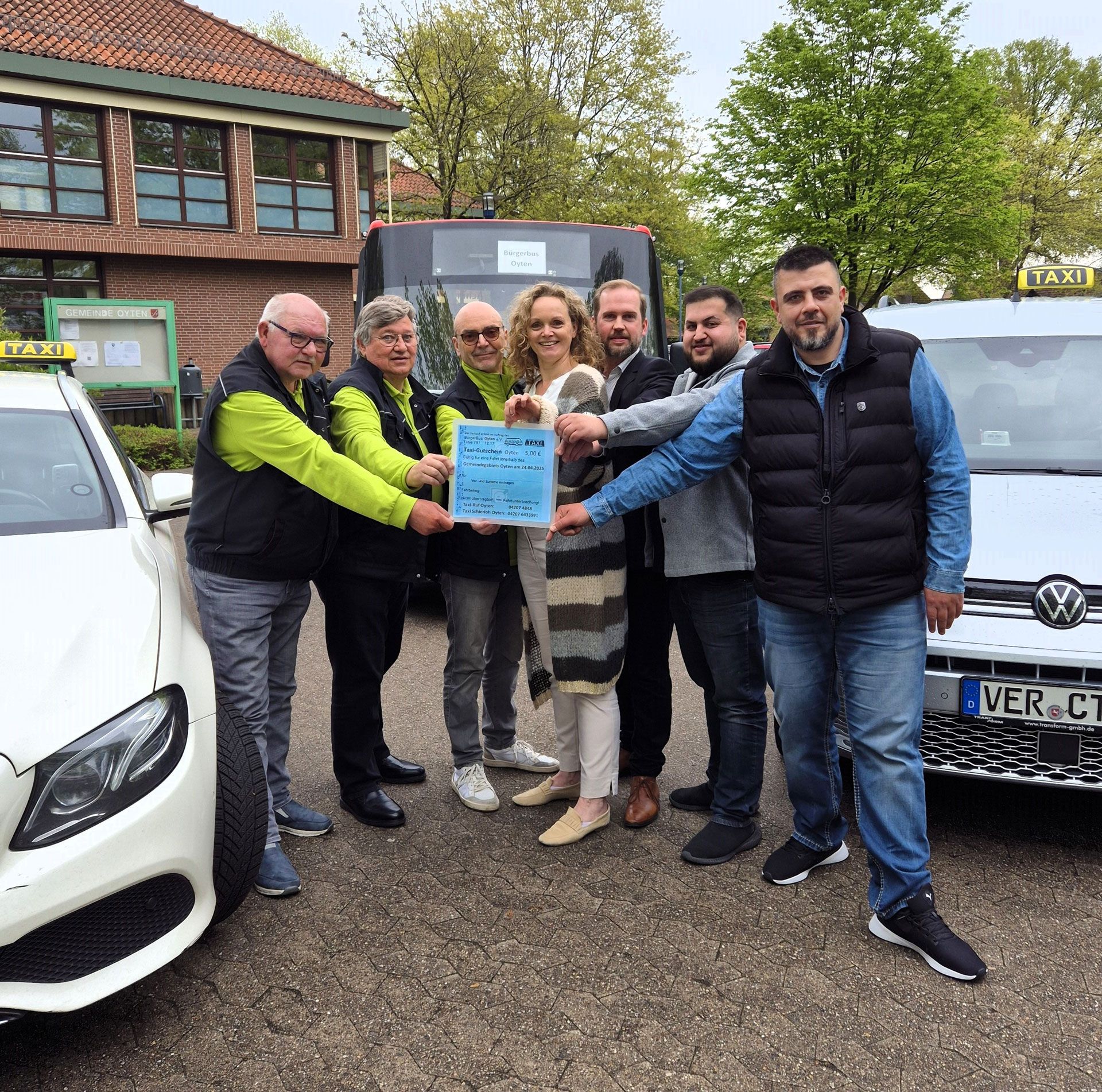 Achim Marek, Dittmar Schmidt und Horst Schneider vom BürgerBus Oyten e.V., Bürgermeisterin Sandra Röse, Fachdienstleiter Marco Schaubitzer sowie die Taxiunternehmer Selcuk Ersu und Mahmut Göc präsentieren ihre Kooperation zum neuen Taxigutschein.
